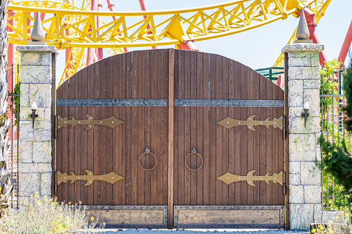 Wooden fabulous rounded gates in medieval style in an amusement park on sunny day.