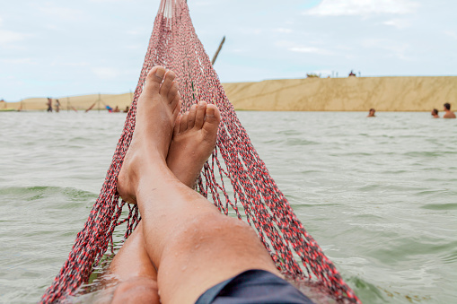 Resting in a hammock on the edge of the tatajuba lagoon in jericoacoara ceará brazil. Traditional hammock in the sea in Jeri. Rest hammock concept. vacation rest concept.