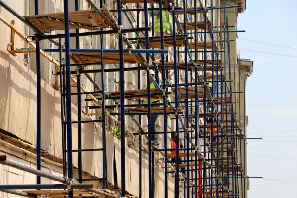 Scaffolding on the old building facade Workers repair house wall, applying cladding and plastering steeplejack stock pictures, royalty-free photos & images