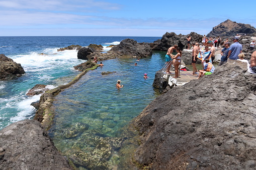 Garachico, Tenerife, Canary Islands, Spain, July 6, 2022: Many tourists enjoy the sun and sea water in one of the natural pools El Caleton, Garachico, Tenerife. Spain