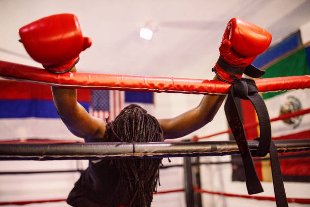 Female fighter with red gloves resting in a boxing ring