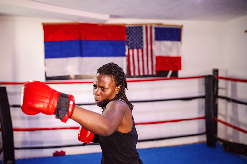 Female fighter with red gloves in a boxing ring