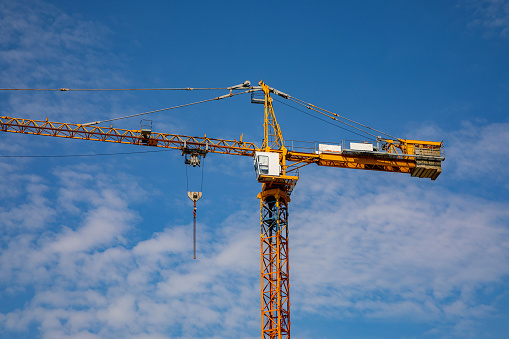 Construction crane on a background of blue sky on a sunny day lifts loads.