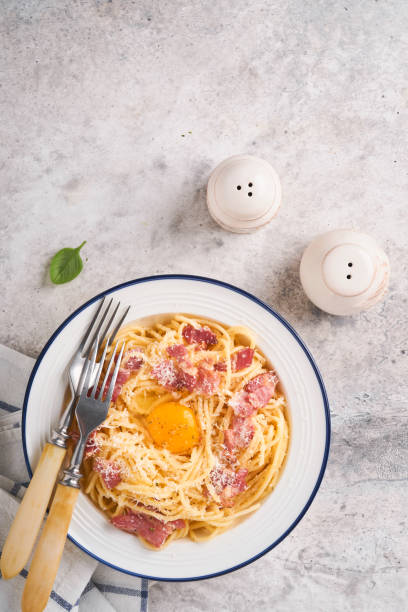 istock Carbonara pasta. Spaghetti with pancetta, egg, parmesan cheese and cream sauce on old gray concrete table background. Traditional italian cuisine and dish. Pasta alla carbonara. Top view. 1407369312