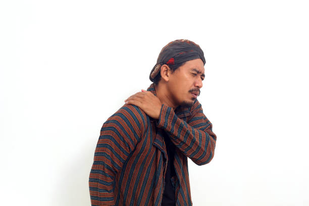 Asian man in java traditional costume suffering in shoulder pain. Isolated on white background