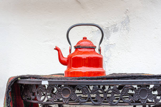 Old red teapot on the metal table stock photo