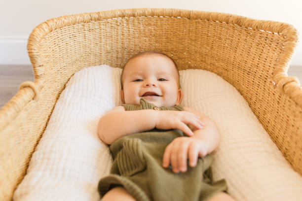 istock A Happy 27-Week-Old Baby Boy Smiling While Wearing an Olive Green Knit Romper While Laying in a Cozy Cotton Blanket in a Seagrass Moses Basket in a Neutral Modern Home 1407371784