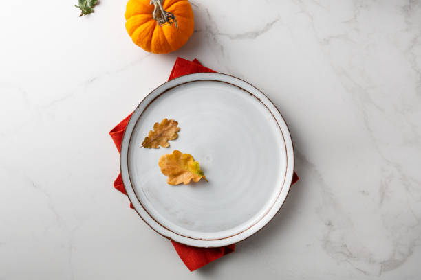 istock White plate autumn leaves and pumpkin holiday concept 1407377704