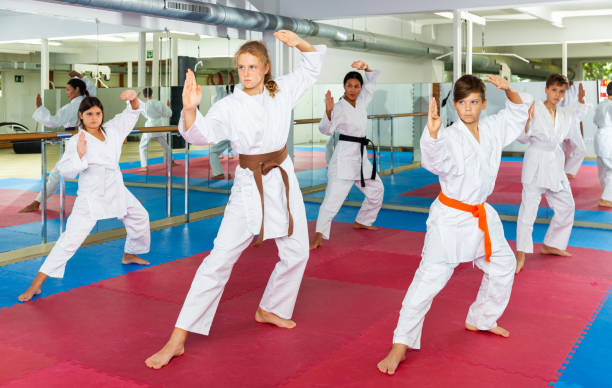 istock Teenagers in kimonos practicing effective karate techniques in group workout at training gym 1407380193