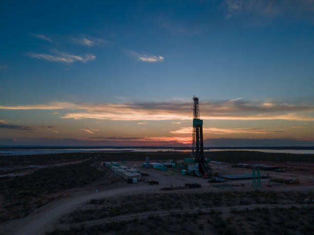 plataforma de perforación que crea un pozo de gas o petróleo silueteado al anochecer bajo un dramático cielo al atardecer - oil industry industry new mexico oil drill fotografías e imágenes de stock