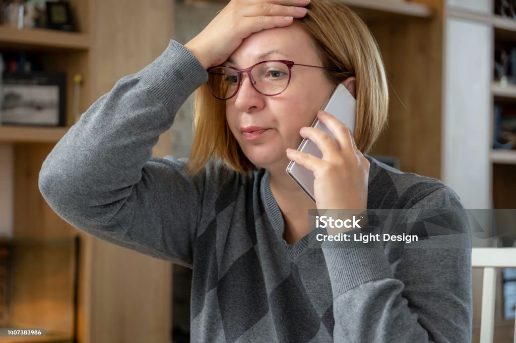 Managing a ton of tasks from home Shot of an adult businesswoman sitting alone in her home office and feeling stressed while using her cellphone 50-54 Years Stock Photo