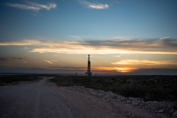 plataforma de perforación que crea un pozo de gas o petróleo silueteado al anochecer bajo un dramático cielo al atardecer - oil industry industry new mexico oil drill fotografías e imágenes de stock