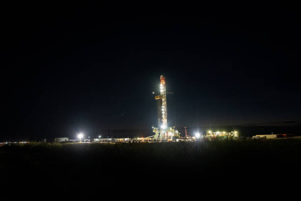 plan de nuit d’un engin de forage de fracturation créant un puits de gaz ou de pétrole brut avec un éclat de lune en arrière-plan contre un ciel nocturne clair - oil industry industry new mexico oil drill photos et images de collection