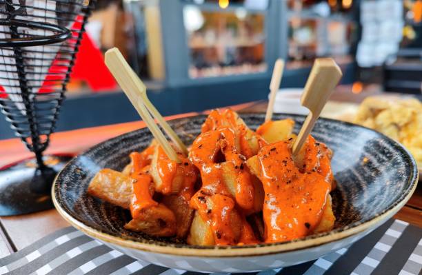 Delicious patatas bravas with spicy orange traditional sauce served on a black dish in a restaurant Delicious patatas bravas with spicy orange traditional sauce served on a black dish in a restaurant. There are no people or trademarks in the shot. patatas bravas stock pictures, royalty-free photos & images