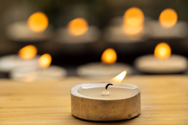 istock Tea candle light on wooden table with blurred background. 1407389373