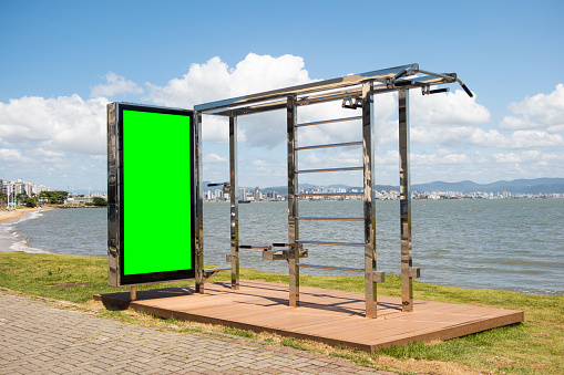Chroma key digital advertising board on an exercise machine in front of a beach