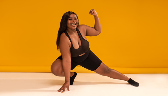 istock Happy plus size woman posing in sporty black fashionable clothes, smiling to the camera. Sports and weight loss concept. Full length photo. 1407390660