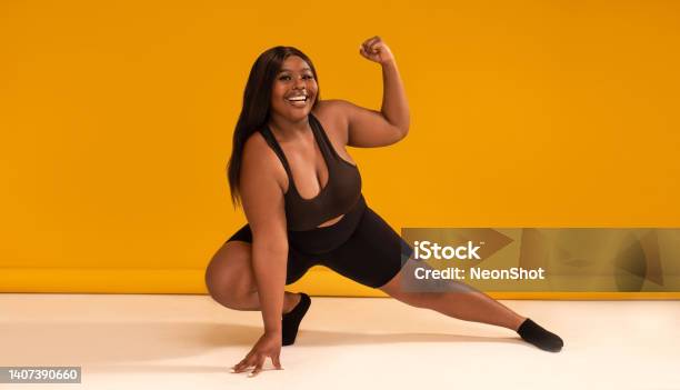 Happy plus size woman posing in sporty black fashionable clothes, smiling to the camera. Sports and weight loss concept. Full length photo.