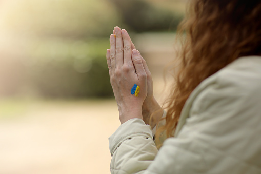 Stop War. Peace in Ukraine. woman hands with picture of flag of ukraine, hands folded in prayer. Antiwar support concept. High quality photo