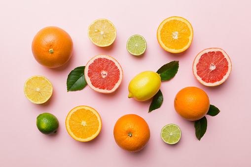 Fruit background. Colorful fresh fruits on colored table. Orange, lemon, grapefruit Space for text healthy concept. Flat lay, top view, copy space.