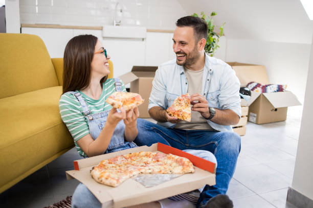 istock Young couple eating pizza while moving into a new apartment 1407408797