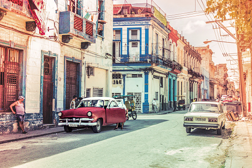 Havana, Cuba - July 08 2018 : A normal street view with vintage cars. Photo is vibrant in colors as it is made in high summer. We see old american and russian cars on the street.