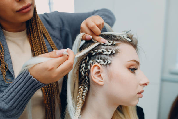 Hairstylist braided afro braids pigtails hair of female client in barber salon stock photo