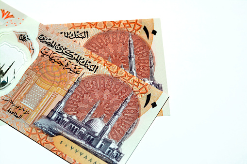 Obverse sides of the new first Egyptian 10 LE EGP ten pounds plastic polymer banknote features Administrative capital's grand mosque Al-Fattah Al-Aleem isolated on white background, selective focus