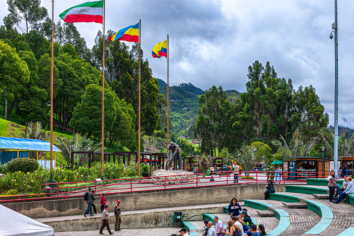 Zipaquira, Colombia - June 30, 2016: Some tourists on the Plaza del Minero near the entrance to the Catedral de Sal, a subterranean church located in an old halite mine, in Zipaquira, in the Cundinamarca Department of the Latin American Country of Colombia. The altitude is 8,690 feet above mean sea level.  People are seen waiting for their turn to enter the mine. Photo shot in the morning sunlight; horizontal format. Copy space.