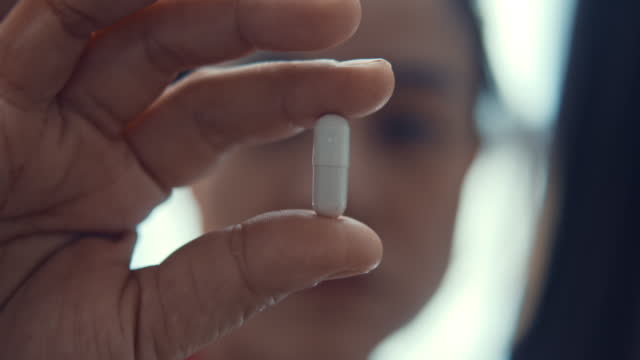 Woman showing a capsule pill,Close-up