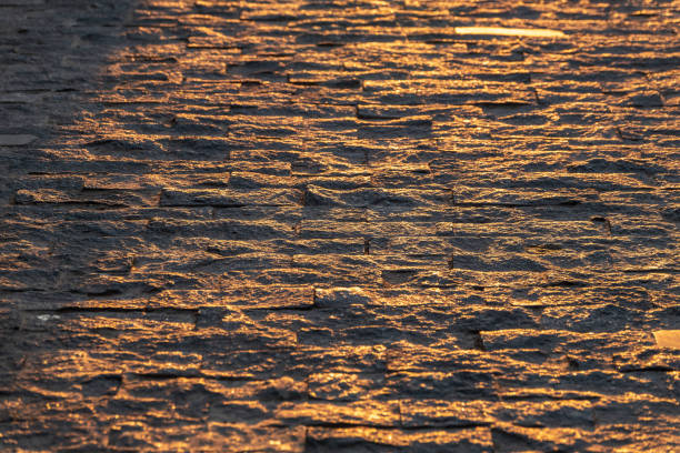 Stone pavement in the rays of the setting sun. Backround of Block pavement on sunset. Texture