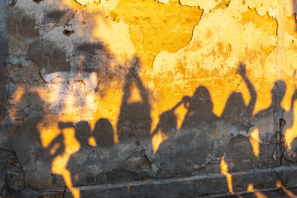 istock Shadows of dancing people on an old stone wall at sunset time. 1407432374
