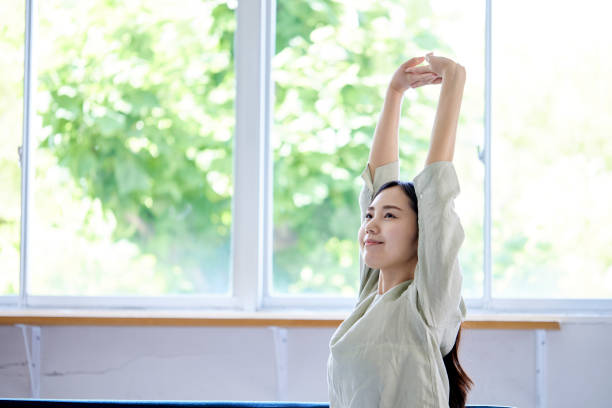 リビングルームでくつろぐ若い日本人女性 - stretching ストックフォトと画像