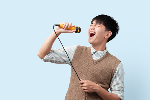 Portrait of young handsome Asian man singing a song with a microphone