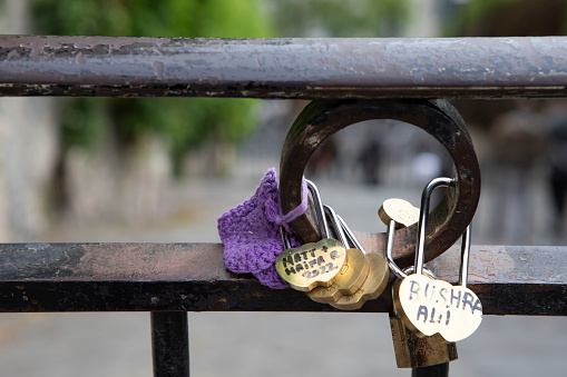 closeup of love padlock on metallic fence on blurred water background