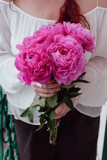 Woman holding a beautiful bouquet of pink peonies for wedding celebration.