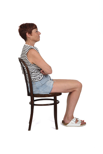 middle aged woman sitting on chair, serious and arms crossed on white background