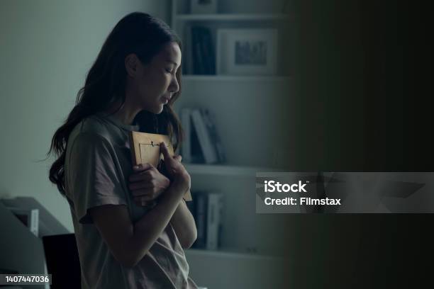Asian Women Holding A Photo Frame Of Lost Loved One And Crying Stock Photo - Download Image Now