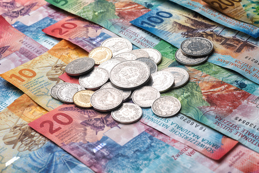 Swiss franc coins on bed of banknotes currency CHF Switzerland