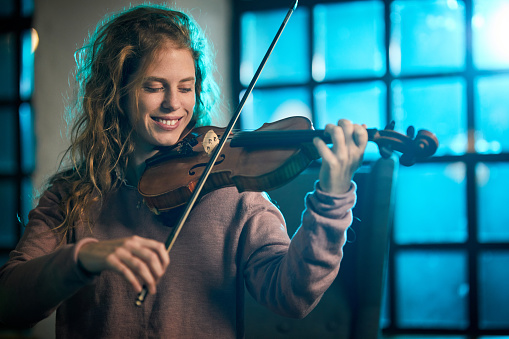 Young happy woman enjoying while playing her violin.