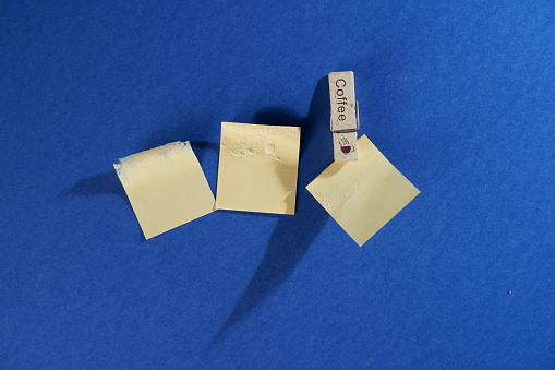 clothespin  and blank adhesive note against blue background