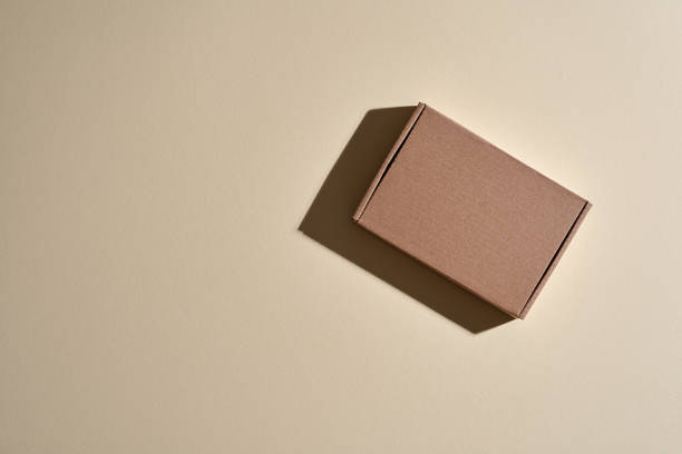 istock top view of small brown cardboard parcel against beige background 1407450076