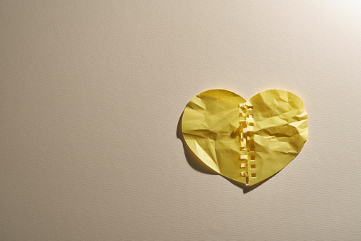 crumpled broken heart paper  against beige background