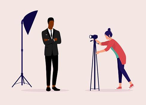 Young Woman Fashion Photographer Taking Photograph Of A Black Male Model Dressed In Elegant Formalwear. Isolated On Color Background.