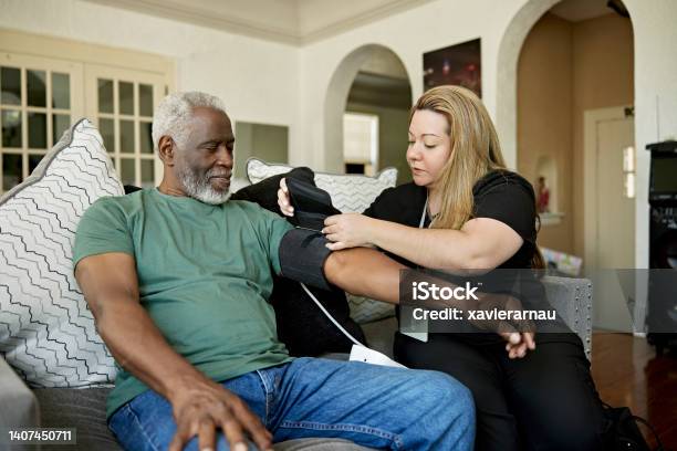 Caregiver attaching blood pressure monitor to senior client