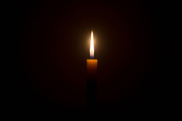 istock A single burning candle flame or light glowing on a Single small yellow candle is isolated on black or dark background on table in church or temple for Christmas, funeral or memorial service 1407451310