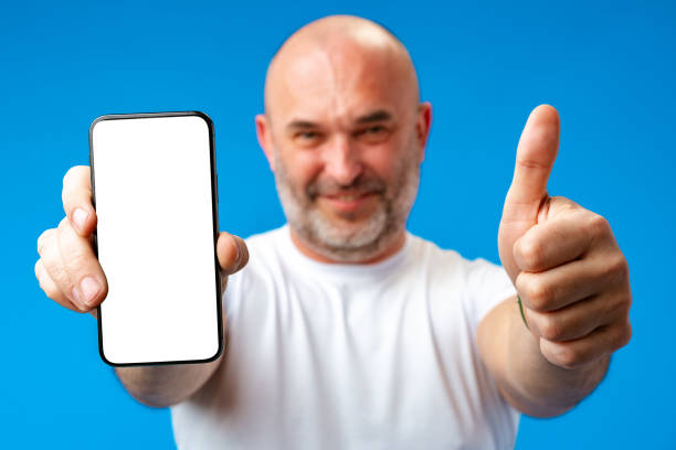 istock Middle-aged man showing blank smartphone screen with copy space against blue background 1407453523