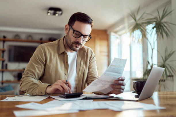 Young man working on his financial bills at home. stock photo