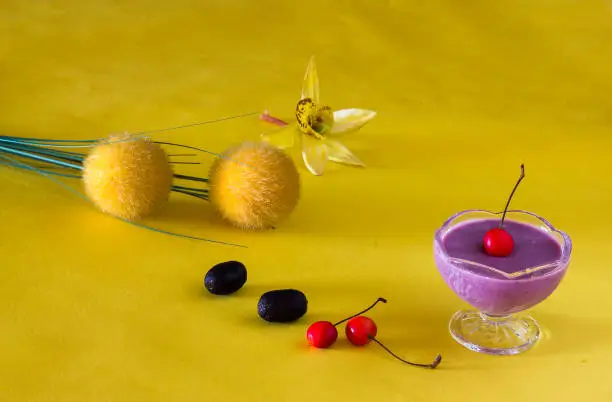 Front view of Jamun Mousse or Java Plum,Black Plum Mousse.Fresh,homemade, vegan dessert made from Jamun - tropical fruit  with cherry toppings.Served in bowls on yellow background.