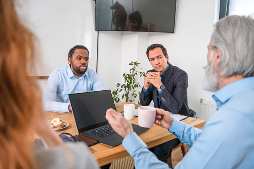 Asian and Black Businessmen Listening To The Business Strategy Proposed by Mature Man